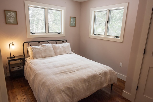 bedroom with dark wood finished floors and baseboards