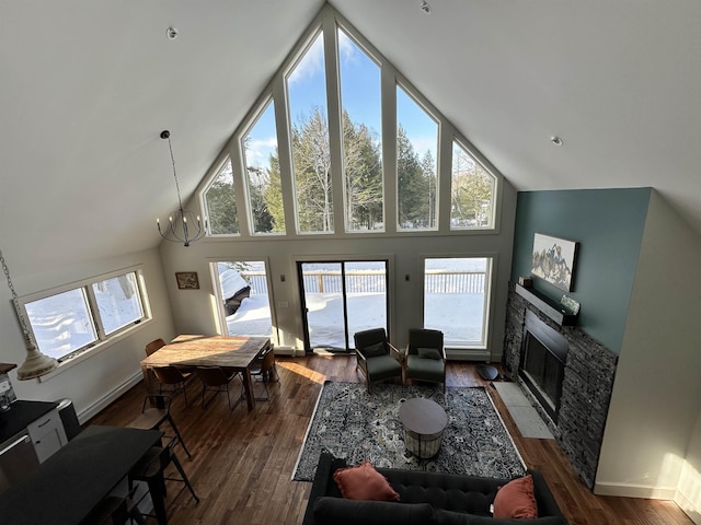 living area featuring a fireplace with flush hearth, dark wood-style flooring, high vaulted ceiling, and an inviting chandelier