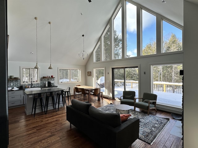 living area with high vaulted ceiling, dark wood finished floors, and a chandelier