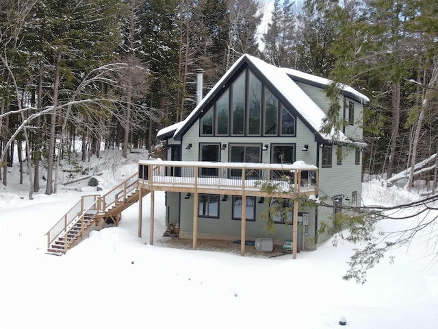 snow covered back of property featuring stairs and a wooden deck