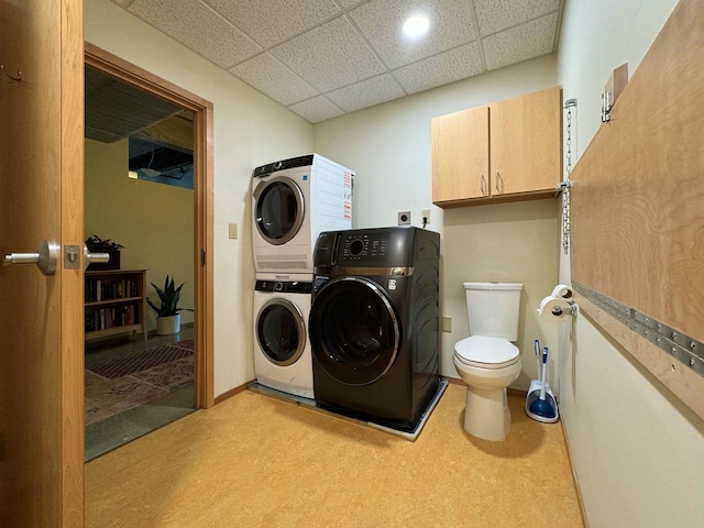 laundry area featuring laundry area, washer and clothes dryer, stacked washing maching and dryer, and baseboards