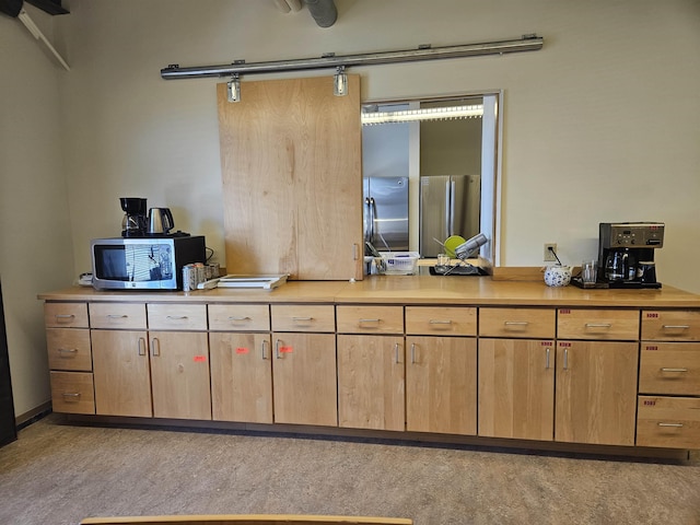 kitchen with a barn door, appliances with stainless steel finishes, light countertops, and light brown cabinetry