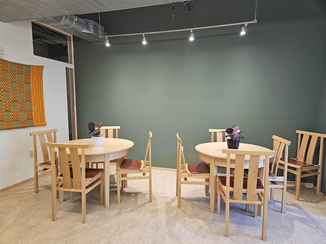 dining space featuring light carpet and baseboards