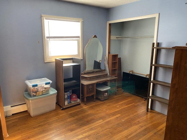 bedroom featuring a baseboard radiator, a closet, and wood finished floors