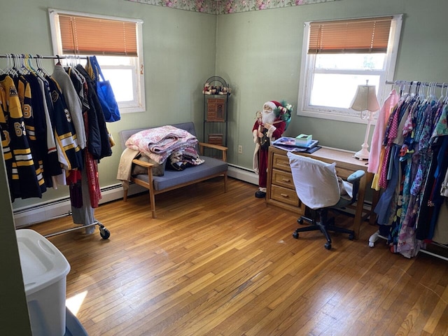 bedroom with a baseboard heating unit and wood finished floors