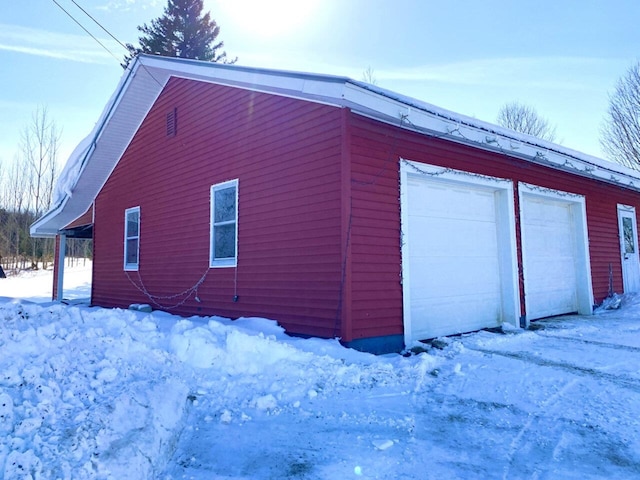 view of snowy exterior with a garage and an outdoor structure