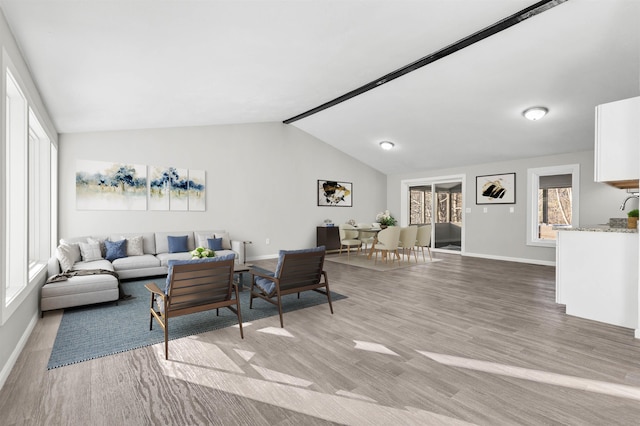 living room featuring vaulted ceiling, light wood-type flooring, and baseboards