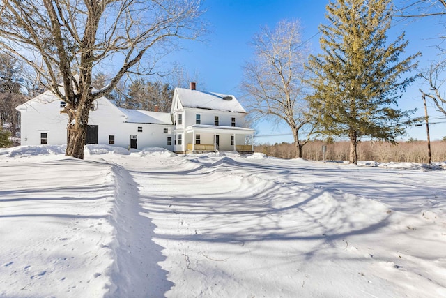 snow covered house featuring a chimney