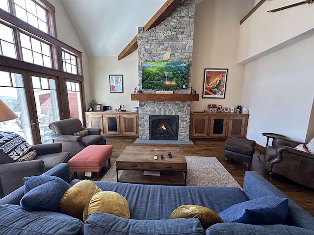 living room with high vaulted ceiling, a stone fireplace, dark wood-style flooring, and french doors