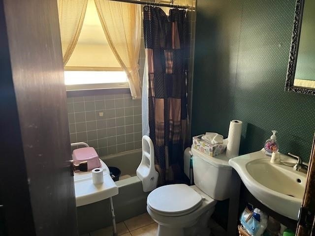 bathroom with shower / bath combination with curtain, wallpapered walls, toilet, a sink, and tile patterned floors