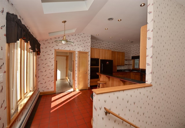 kitchen featuring black appliances, wallpapered walls, vaulted ceiling with skylight, and a peninsula