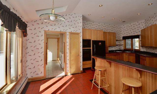 kitchen with a peninsula, wallpapered walls, a breakfast bar area, and washer and dryer