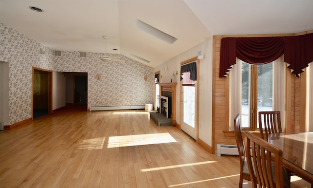 interior space with lofted ceiling, a baseboard radiator, and wallpapered walls