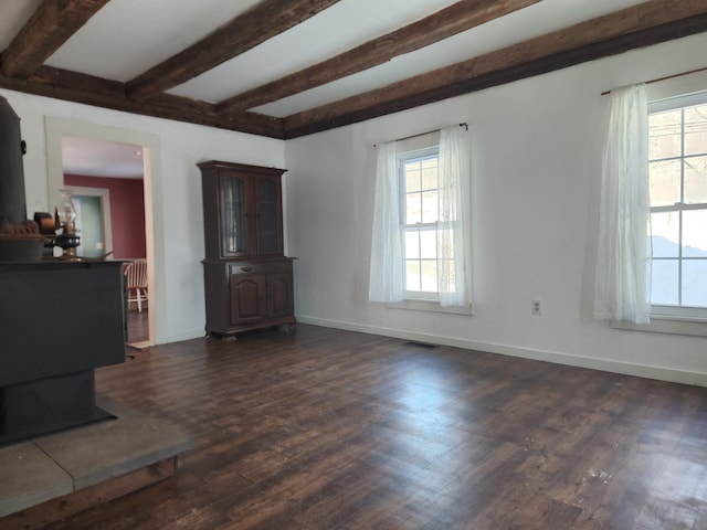 unfurnished living room with dark wood-style flooring, plenty of natural light, visible vents, and baseboards