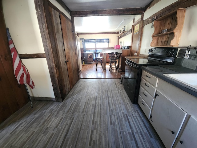 kitchen featuring beam ceiling, open shelves, dark countertops, dark wood-type flooring, and black / electric stove