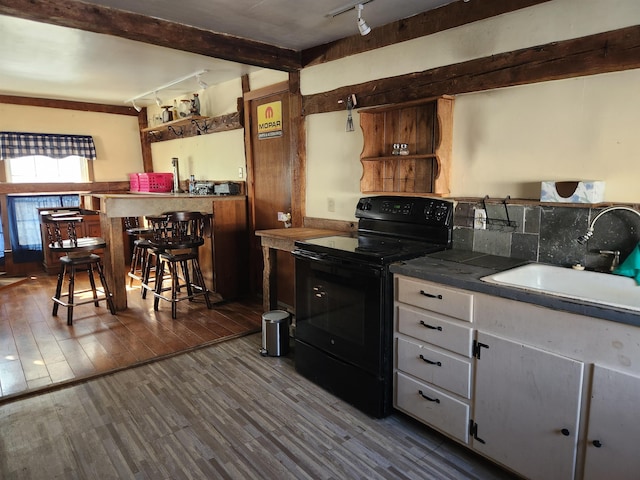 kitchen featuring beamed ceiling, black range with electric stovetop, wood finished floors, rail lighting, and a sink