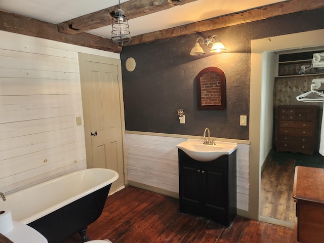 bathroom featuring a freestanding tub, wood finished floors, beamed ceiling, and vanity