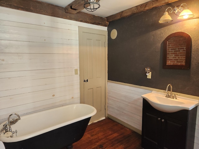 bathroom featuring a freestanding tub, wooden walls, wood finished floors, vanity, and beamed ceiling