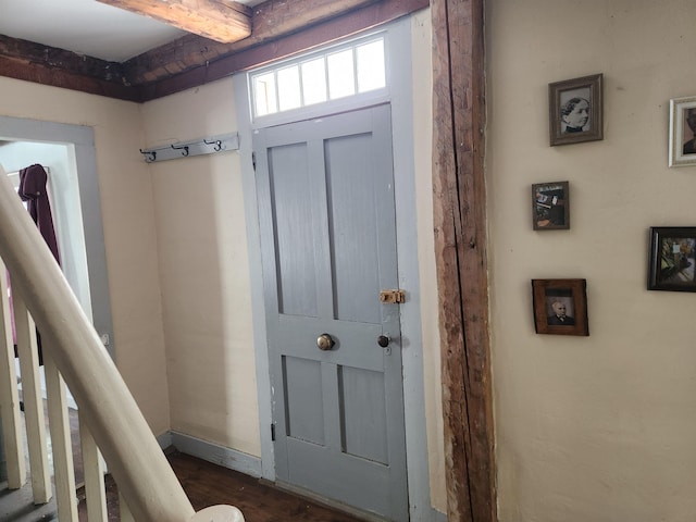 doorway with baseboards, dark wood-type flooring, and beam ceiling