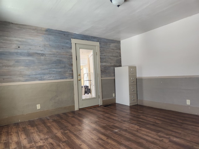 empty room featuring a wainscoted wall and dark wood-style flooring