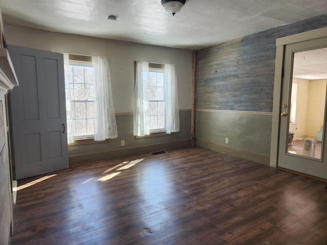 foyer with dark wood-style floors, wainscoting, visible vents, and wooden walls