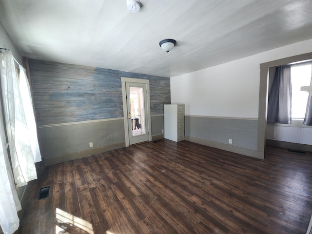 spare room with dark wood-style floors, wainscoting, and visible vents