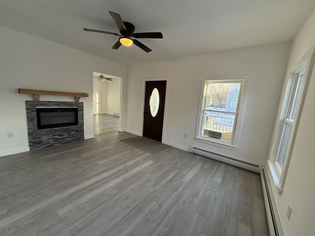 unfurnished living room with baseboard heating, a fireplace, light wood-style flooring, and baseboards