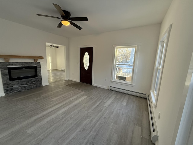 foyer entrance with light wood finished floors, baseboards, a baseboard radiator, baseboard heating, and a stone fireplace