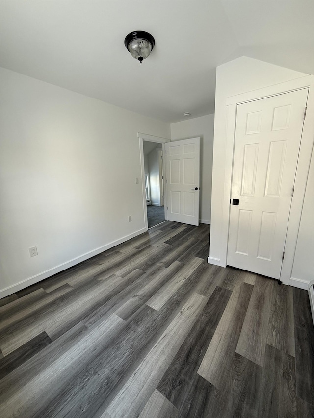 unfurnished bedroom with dark wood-type flooring and baseboards