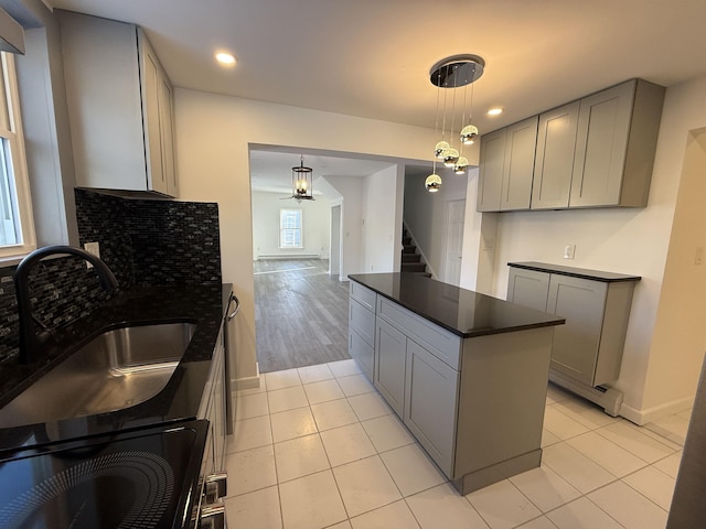 kitchen featuring dark countertops, pendant lighting, a sink, and gray cabinetry