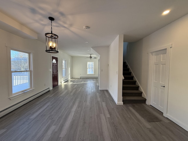 foyer featuring stairway, a baseboard radiator, dark wood finished floors, and a wealth of natural light