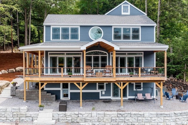 back of house featuring a shingled roof and a wooden deck