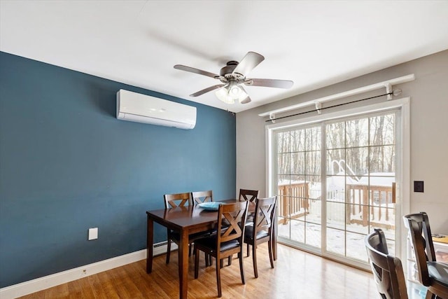 dining room featuring light wood-style flooring, baseboards, a ceiling fan, and a wall mounted AC