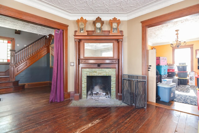 living room with an ornate ceiling, crown molding, dark wood finished floors, a fireplace, and stairway