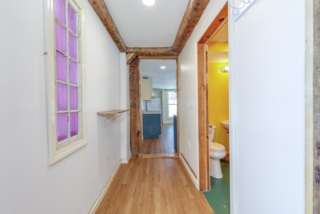 corridor with light wood-type flooring and baseboards