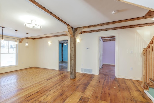 empty room with light wood-style floors, visible vents, and baseboards