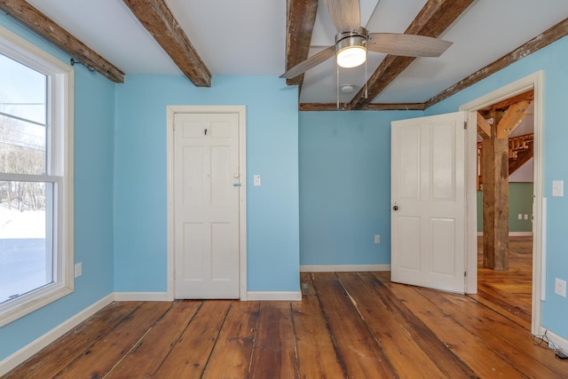 spare room featuring ceiling fan, dark wood finished floors, beam ceiling, and baseboards