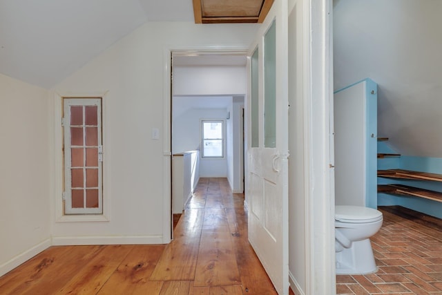 interior space featuring light wood-type flooring, vaulted ceiling, and baseboards