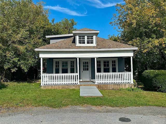 bungalow featuring covered porch, a front lawn, and roof with shingles