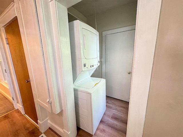 laundry area featuring light wood-type flooring, laundry area, and stacked washer / drying machine