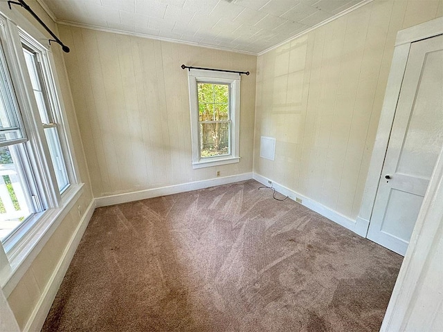 carpeted spare room featuring baseboards and crown molding