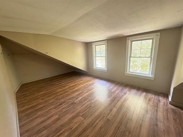 spare room with a textured ceiling, wood finished floors, and lofted ceiling