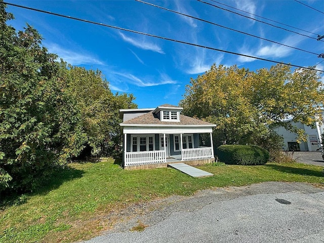 view of front of home featuring a front yard, covered porch, and roof with shingles