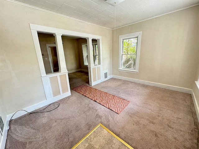 empty room featuring carpet floors, ornamental molding, visible vents, and baseboards