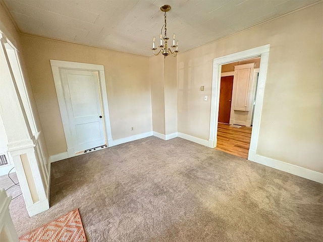 spare room with carpet, visible vents, baseboards, and a notable chandelier