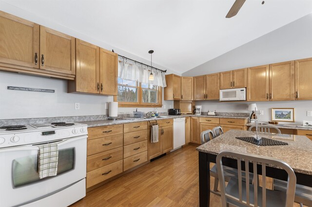 kitchen featuring pendant lighting, light wood finished floors, lofted ceiling, light stone countertops, and white appliances