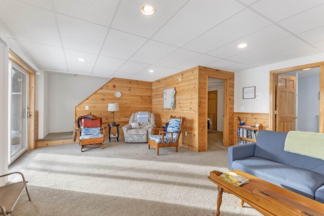 carpeted living room featuring wooden walls, a drop ceiling, and recessed lighting