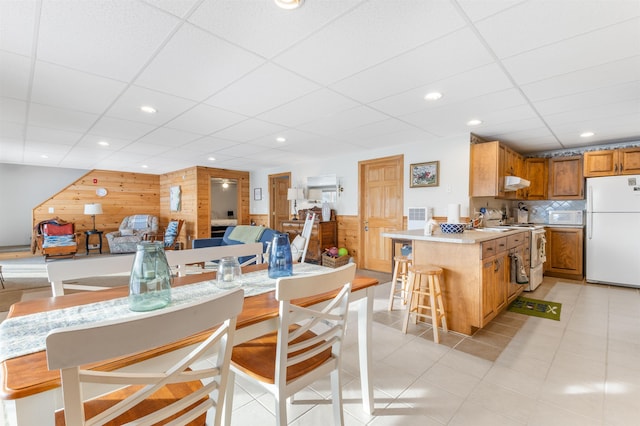 kitchen featuring a breakfast bar area, light countertops, open floor plan, white appliances, and under cabinet range hood