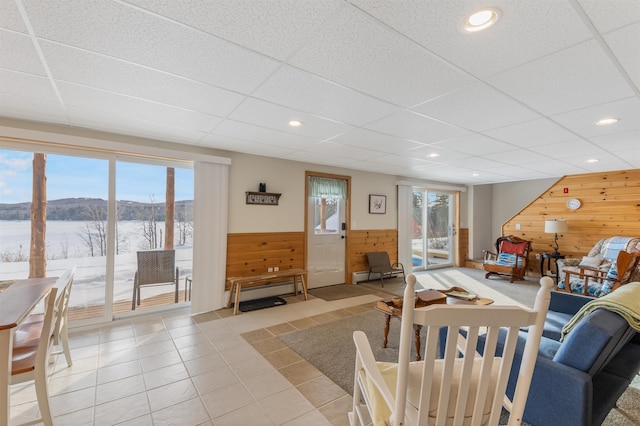 living room featuring light tile patterned floors, recessed lighting, wainscoting, wooden walls, and a drop ceiling