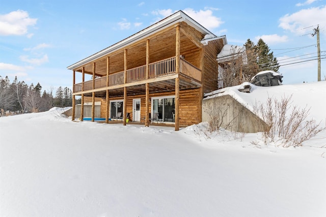 snow covered back of property featuring a balcony